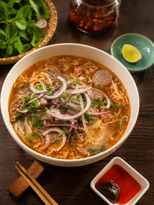 Vietnamesisk nudelsoppa med skivat nötkött, rödlök, färska örter och lime