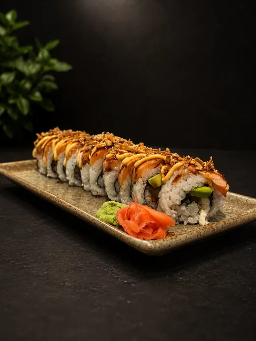 Maki-rulle med lax, unagisås, sesamfrö och rostad lök på keramikfat